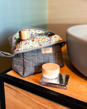 Szara lniana kosmetyczka w kształcie box, zamknięta, widok z góry, na jasnym tle