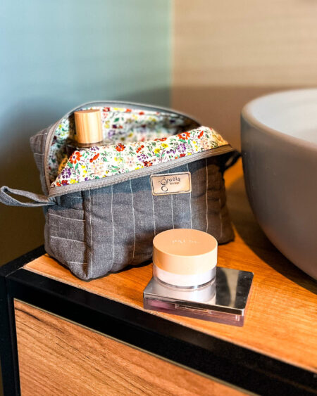 Szara lniana kosmetyczka w kształcie box, zamknięta, widok z góry, na jasnym tle