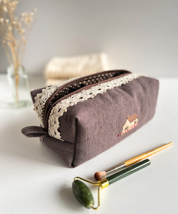 Detal ręcznego haftu domku na lnianej kosmetyczce