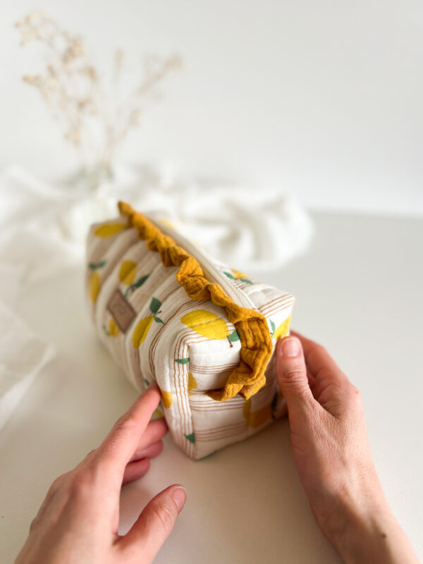 Kosmetyczka w cytrynki z falbanką ustawiona na toaletce, dekoracyjna saszetka na kosmetyki w świeżym letnim stylu.