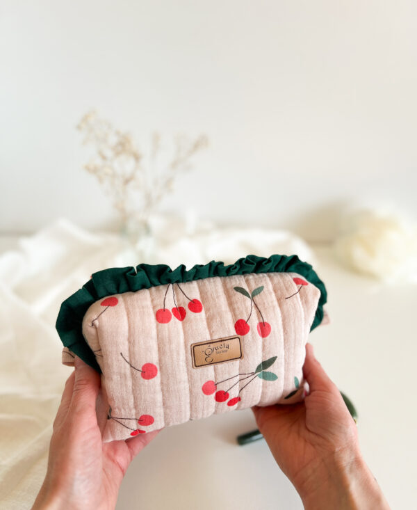 Kosmetyczka w czereśnie z falbanką otwarta, pokazująca przestronne wnętrze na makijaż, kosmetyki i drobne akcesoria.