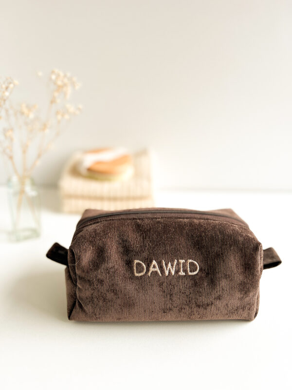 Minimalistyczna kosmetyczka z brązowego sztruksu z personalizowanym haftem, na neutralnym tle
