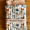 Zbliżenie na personalizowane etui na książkę z haftem oraz bawełnianym wzorem w sowy i książki.
