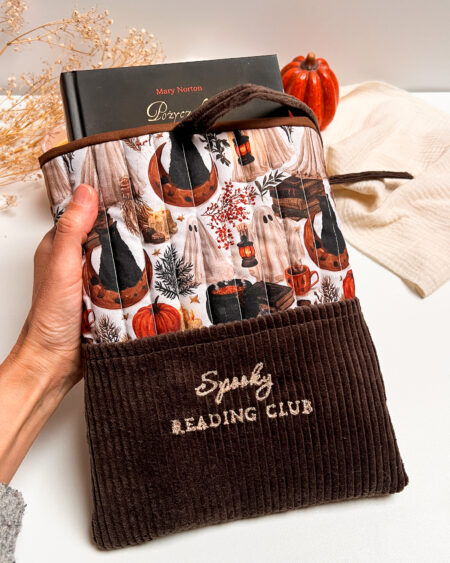 Ręcznie szyte brązowe etui na książkę Spooky Reading Club z kieszonką, jesiennym wzorem książek, dyń i czarnych kotów.